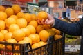 A man`s hand takes a ripe orange from a box with oranges in a supermarket. Royalty Free Stock Photo