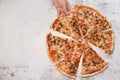 Man`s hand taking a slice of pizza. White stone background and space for text
