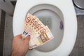 Man`s Hand Throwing Fifty Euro Notes In Toilet