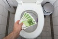 Man`s Hand Throwing Hundred Euro Notes In Toilet