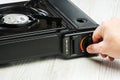 A man's hand turns on a portable gas stove on a wooden table Royalty Free Stock Photo