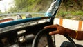 Man's hand turns steering wheel of mouving autorickshaw on road of Rishikesh