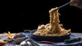 Man`s hand using chopsticks to pick up stir fry instant noodles spicy seafood in black plate with various spices on black slate i