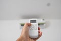 Man`s hand using remote controler. Hand holding rc and adjusting temperature of air conditioner mounted on a white wall Royalty Free Stock Photo