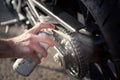 Man`s hand using spray can to clean and protect motorbike chain. Concept of maintenance and lubrication of the motorcycle chain