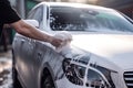 A man\'s hand washes a white car with foam. Generative ai