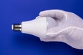 A man`s hand in a white cotton glove with a dowe lamp on the blue