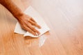 A man`s hand wiping a white cream stain on the wooden floor with a tissue Royalty Free Stock Photo