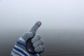 A man`s hand in a woolen glove. In the palm of his hand the lid from the camera lens is clamped. There is a mist above water in Royalty Free Stock Photo