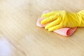 A man`s hand in a yellow rubber glove oil polishes the wooden surface of the table, the floor with a pink rag. Royalty Free Stock Photo