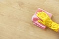 A man`s hand in a yellow rubber glove oil polishes the wooden surface of the table, the floor with a pink rag. Royalty Free Stock Photo