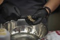 Man`s hands in black gloves with knife and shucking fresh oysters on a seafood market. Gastronomic dainty products on