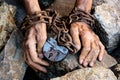 Man`s hands are chained. Big old iron castle. Big gray stones. The thin, dirty hands of a slave wrapped in an old rusty