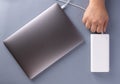 Man`s hands charge laptop with power bank by white USB cable. Royalty Free Stock Photo