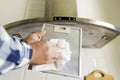 Man`s hands cleaning aluminum mesh filter for cooker hood. Housework and chores. Kitchen cooker hood on the background