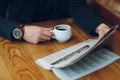 Man`s hands close-up holding cup of coffee and a newspaper Royalty Free Stock Photo