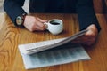 Man`s hands close-up holding cup of coffee and a newspaper Royalty Free Stock Photo