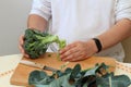 Man's hands cutting freh raw broccoli with kitchen knife