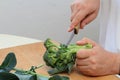 Man's hands cutting freh raw broccoli with kitchen knife