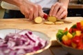 Man`s hands cutting fresh tomatos in the kitchen, preparing a meal for lunch. Topdown view. Royalty Free Stock Photo