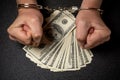 Man s hands in handcuffs and many hundred dollar american banknotes on black background. The concept of corruption Royalty Free Stock Photo