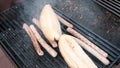 Man`s hands with the help of tongs put a hotdog in a bread roll. A street chef in black gloves warms sausages and bread