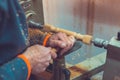 Man`s hands hold chisel near lathe, man working at small wood lathe, an artisan carves a piece of wood using a manual lathe Royalty Free Stock Photo