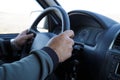 Man`s hands hold steering wheel, driving a vehicle piloting a car in motion while traveling on a trip Royalty Free Stock Photo