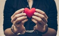 Man`s hands holding as a red heart together with hand cuffs Royalty Free Stock Photo