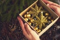 man's hands holding box with gold christmas decorations. Design Royalty Free Stock Photo