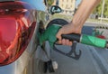 Man`s hands holding the gas pump, refueling his car with fuel close-up across city streets. Energy industry. Gas station business/ Royalty Free Stock Photo