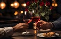 Man\'s hands holding hands of girl on restaurant table day light with two red wine glasses and red roses Royalty Free Stock Photo