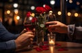 Man\'s hands holding hands of girl on restaurant table day light with two red wine glasses and red roses Royalty Free Stock Photo