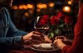 Man\'s hands holding hands of girl on restaurant table day light with two red wine glasses and red roses Royalty Free Stock Photo