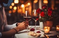 Man\'s hands holding hands of girl on restaurant table day light with two red wine glasses and red roses Royalty Free Stock Photo