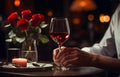 Man\'s hands holding hands of girl on restaurant table day light with two red wine glasses and red roses flower Royalty Free Stock Photo