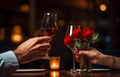 Man\'s hands holding hands of girl on restaurant table day light with two red wine glasses and red roses flower over white Royalty Free Stock Photo