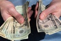 Man`s hands holding out piles of cash in American five and twenty dollar bills Royalty Free Stock Photo
