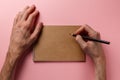 Man`s hands holding pencil and spiral notepad as mockup for your design. Pink background. Top view. Flat lay. Pastel background Royalty Free Stock Photo