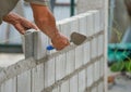 Man`s hands of industrial bricklayer with aluminium brick trowel installing brick blocks on construction site