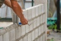 Man`s hands of industrial bricklayer with aluminium brick trowel installing brick blocks on construction site, selective focus a