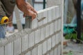 Man`s hands of industrial bricklayer with aluminium brick trowel installing brick blocks on construction site