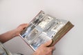 ManÃ¢â¬â¢s hands of an old man holding an old retro album with vintage monochrome photographs in sepia color, the concept of