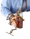 Man`s hands in old rusty chains near the bottle. Isolated on white background. Addicted to alcohol. In the trap of office work.