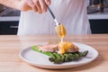 Man`s hands pouring hollandaise sauce on top of delicious baked salmon with steamed green asparagus