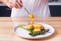 Man`s hands pouring hollandaise sauce on top of delicious baked salmon with steamed green asparagus Royalty Free Stock Photo