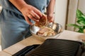 The man`s hands prepares delicious juicy meat steak on an electric grill on wooden table. Smoke in the home kitchen