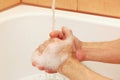Man`s hands with soap under jet of water in the bathroom Royalty Free Stock Photo