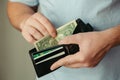 The man`s hands take out 1 dollar bills from an empty wallet. Poverty concept, crisis. dismissal or cost savings