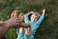 Man\'s Hands Tickle A Child\'s Bare Feet Lying On The Grass